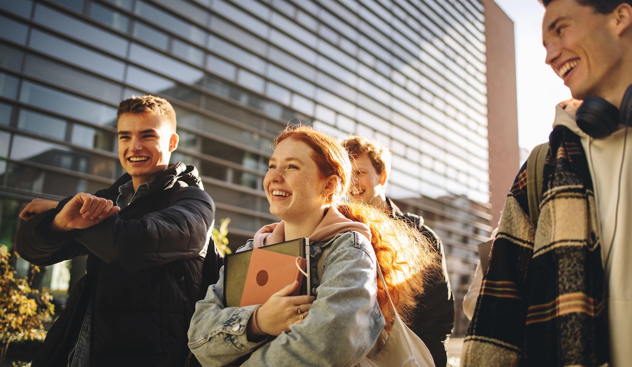 A group of smiling college students walking together outside a college campus.